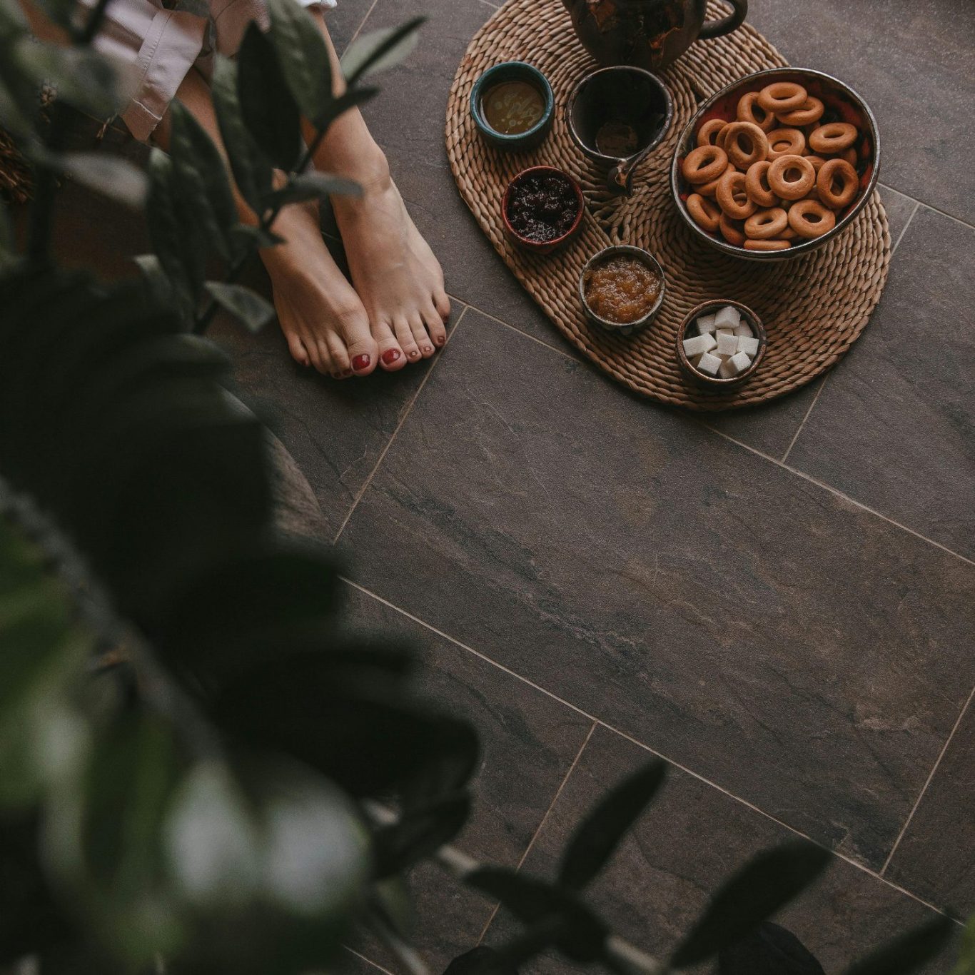 Tasse mit heißen Getränken und Snacks auf einem Tisch neben einem Fuß und Pflanzen.