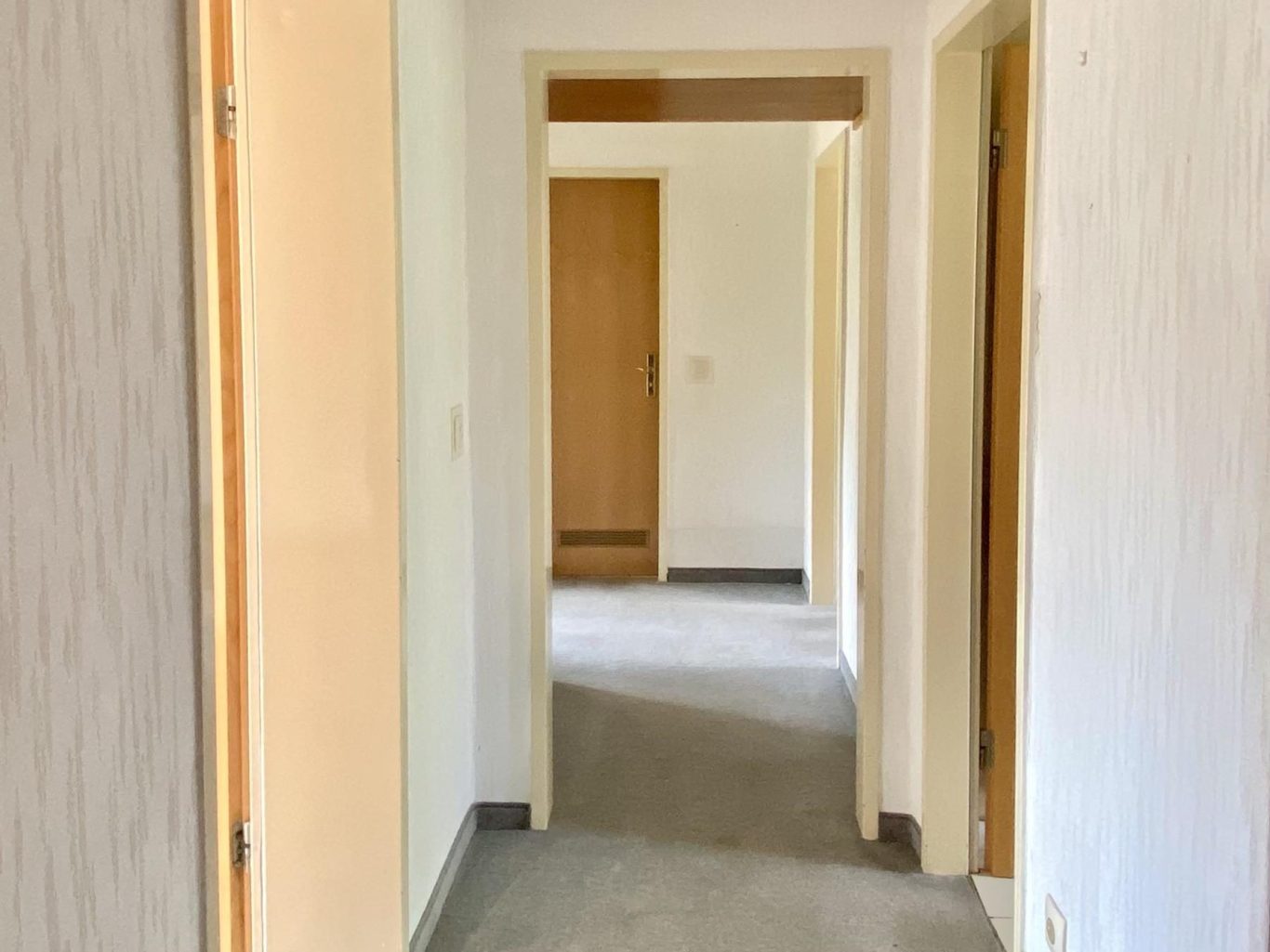 Ein altmodischer Flur mit vielen Türen und Teppichboden.